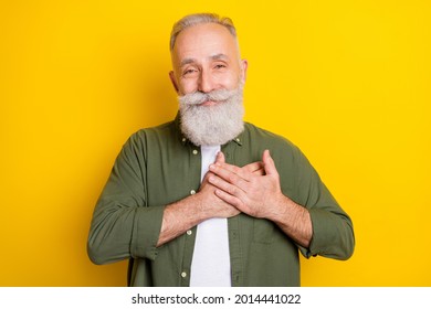 Photo portrait of senior man smiling thankful keeping hands on chest isolated vibrant yellow color background