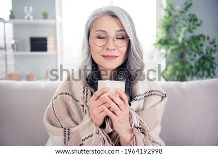 Photo portrait of senior woman dreamy smiling drinking hot tea sitting under plaid blanket at home