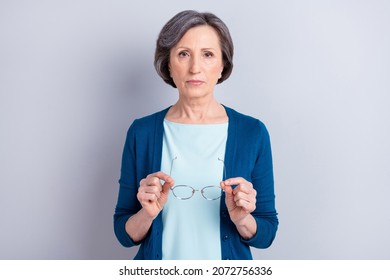 Photo Portrait Of Serious Senior Woman Keeping Glasses Wearing Blue Cardigan Isolated On Grey Color Background Copyspace