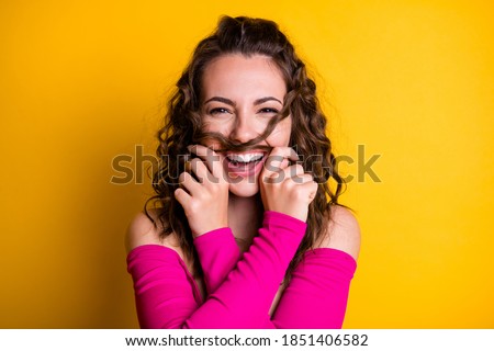 Photo portrait of silly brunette girl making hair mustache laughing holding with two hands wearing fuchsia crop-top isolated on vivid yellow colored background