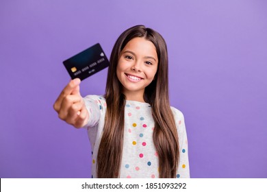 Photo portrait of smiling little girl with long brunette hair showing blurred debit card isolated on bright purple color background - Shutterstock ID 1851093292