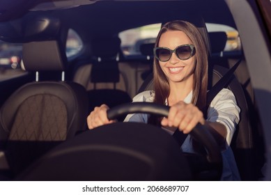 Photo portrait smiling woman wearing sunglass keeping steering wheel in the car