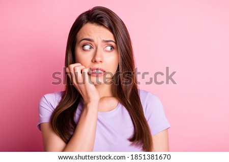 Photo portrait of terrified girl biting nails isolated on pastel pink colored background