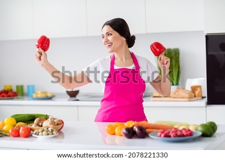 Photo portrait woman in apron dancing with red paprika in the kitchen