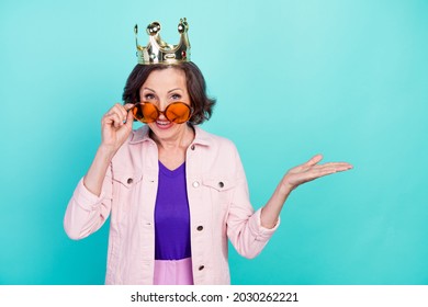 Photo portrait woman in golden crown sunglass smiling keeping blank space on hand isolated vivid turquoise color background - Powered by Shutterstock