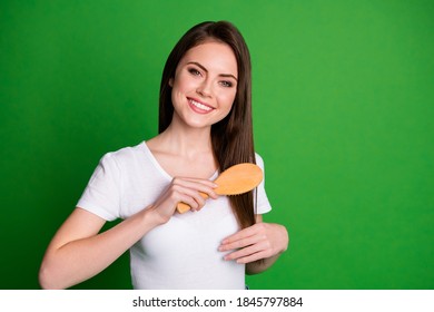 Photo portrait of woman grooming hair with brush isolated on vivid green colored background