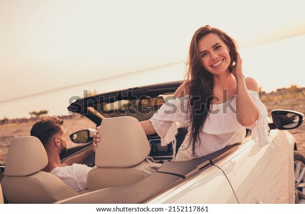 Photo portrait woman\
riding in cabriolet car on sandy beach wearing white dress enjoying\
warm summer weather
