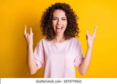 Photo portrait of woman showing tongue making two rock goat signs isolated on vivid yellow colored background