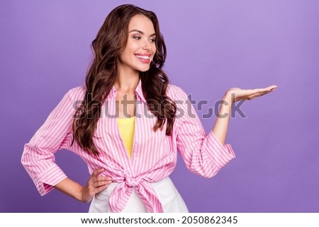 Photo portrait woman smiling in casual clothes showing copyspace on hand cheerful isolated pastel purple color background