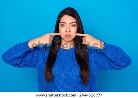Photo portrait young girl playful touching cheeks holding breath isolated vibrant blue color background