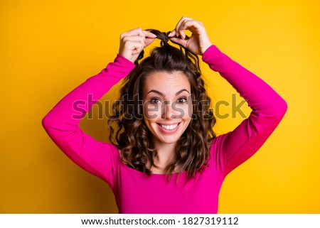 Photo portrait of young woman making ponytail smiling wearing fuchsia crop-top isolated on vivid yellow colored background