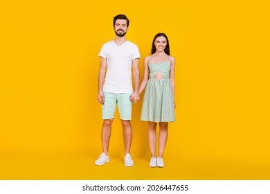 Photo of positive attractive couple hold hands posing wear casual outfit sneakers isolated yellow color background