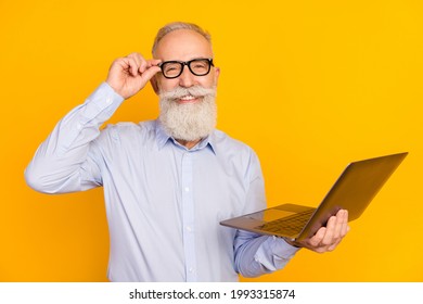 Photo Of Positive Beard Old Man Hold Laptop Wear Spectacles Blue Shirt Isolated On Yellow Color Background