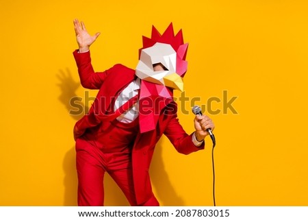 Photo of positive charismatic guy hold mic sing song wear rooster mask red suit isolated yellow color background