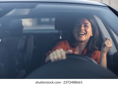Photo of positive cheerful girl funky driver rider enjoy drive ride car under pop star hits playlist music try dance raise hands in city center