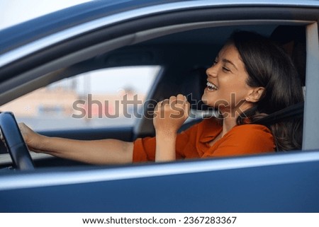 Photo of positive cheerful girl funky driver rider enjoy drive ride car under pop star hits playlist music try dance raise hands in city center