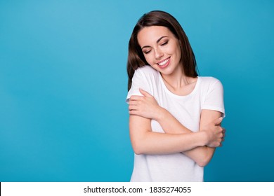 Photo of positive cheerful girl hug herself isolated over blue color background