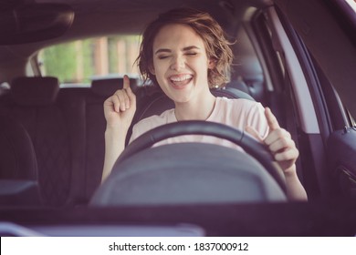Photo of positive cheerful girl ride drive car town route wait traffic jam listen music sound try dance feel excited