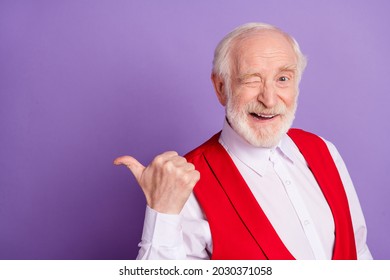 Photo Of Positive Cheerful Happy Old Man Point Finger Thumb Empty Space Wink Isolated On Purple Color Background