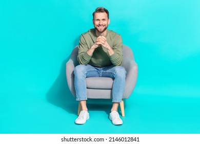 Photo of positive cheerful man sit armchair hold hands beaming shiny smile wear pullover isolated blue color background - Shutterstock ID 2146012841