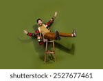 Photo of positive cheerful man wear stylish clothes sit chair isolated on khaki color background