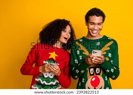 Photo of positive cute lady guy wear new year ugly print sweaters texting apple samsung iphone devices isolated yellow color background