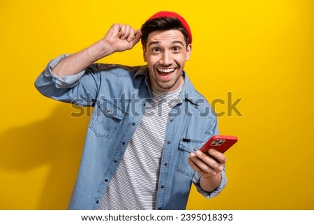 Photo of positive funky guy wear denim jacket chatting apple iphone samsung modern device isolated yellow color background
