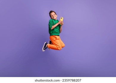 Photo of positive funky hispanic boy pupil wear green stylish sportswear use phone social media isolated on purple color background - Powered by Shutterstock