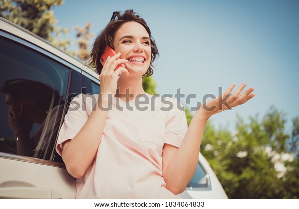 Photo of positive girl car driver rider\
call friend suggest tell say friend summer vacation drive ride\
plans use smartphone in town center\
outdoors