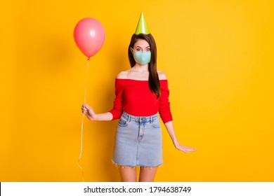 Photo Of Positive Girl In Medical Mask Enjoy Covid Quarantine Anniversary Party Hold Balloon Wear Red Top Denim Jeans Short Mini Skirt Cone Isolated Over Bright Shine Color Background