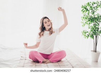 Photo of positive girl sit bed yawn stretching hands up in white room interior - Powered by Shutterstock