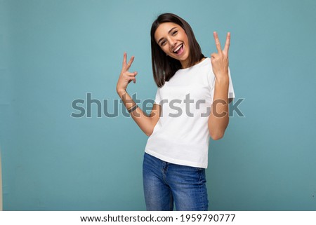 Photo of positive happu funny young fascinating nice brunette woman with sincere emotions wearing casual white t-shirt for mockup isolated over blue background with copy space