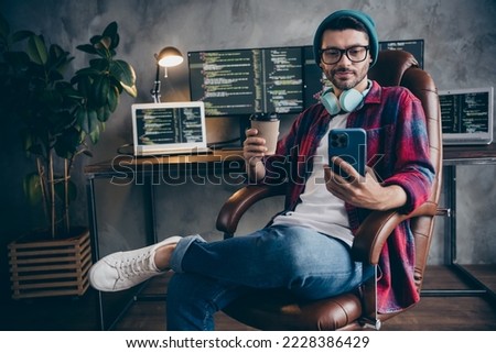 Photo of positive happy guy dressed eyewear earphones reading apple samsung modern gadget indoors workstation workshop home