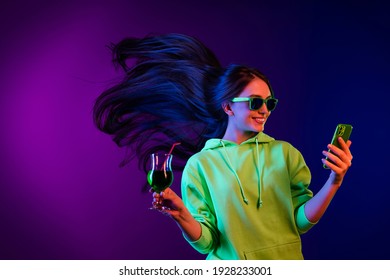 Photo Of Positive Happy Nice Young Woman Look Phone Hold Glass Alcohol Disco Isolated On Neon Background