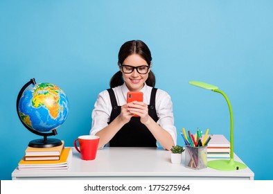 Photo Positive High School Girl Sit Table Geography Globe Use Smartphone Texting Typing Social Media Have Beverage Mug Wear White Blouse Black Overall Uniform Isolated Blue Color Background