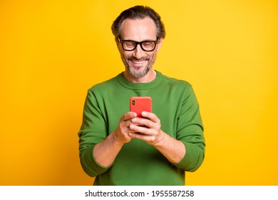 Photo of positive man hold smartphone look screen toothy smile wear glasses green sweater isolated yellow color background - Powered by Shutterstock