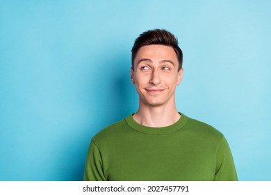 Photo of positive minded man look empty space think thoughts wear green pullover isolated blue color background
