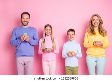 Photo of positive mom dad and little kids hold digital cellphone isolated over pastel color background.