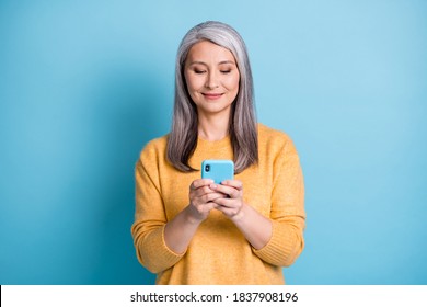 Photo of positive old lady use smartphone read social network news share comment subscribe wear style stylish trendy sweater isolated over blue color background
