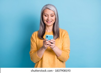 Photo of positive old woman use smartphone follow post repost social media news wear style stylish trendy sweater isolated over blue color background