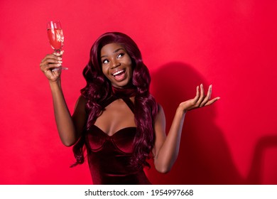 Photo Of Positive Pretty Afro American Woman Look Empty Space Raise Glass Isolated On Red Color Background