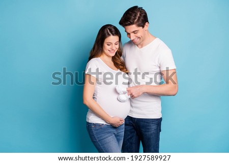 Photo of positive spouse look belly finger baby booties steps playing isolated on blue color background