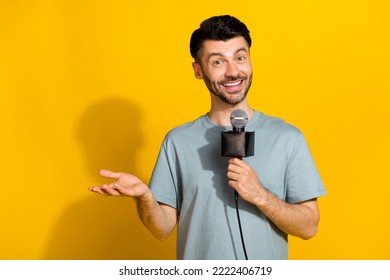 Photo of positive talented man announcer speak mic tell breaking true news empty space isolated on yellow color background