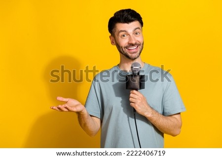 Photo of positive talented man announcer speak mic tell breaking true news empty space isolated on yellow color background