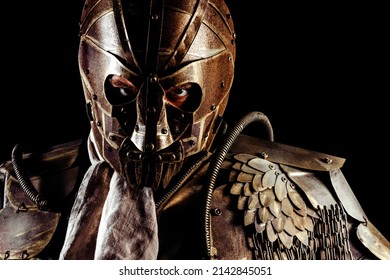 Photo Of Post Apocalyptic Wasteland Warrior Portrait Standing In Armor Mask And Outfit On Black Background.