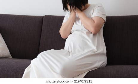 Photo Of A Pregnant Woman Sitting On A Sofa And Covering Her Face With Both Hands