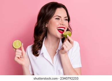 Photo of pretty adorable lady wear white blouse biting sour lime smiling isolated pink color background