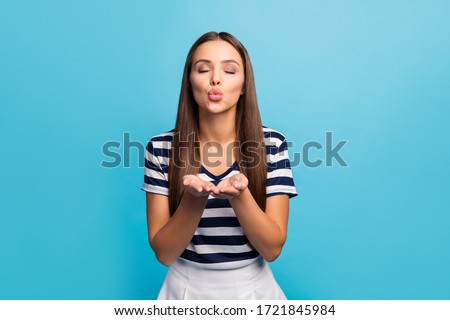 Photo of pretty beautiful lady flirty feminine person hold hands send air kiss handsome guy eyes closed emotions feelings wear white striped t-shirt skirt isolated blue background
