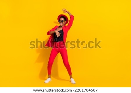 Photo of pretty beautiful short hair person dressed red suit cap dark eyewear dancing isolated yellow color background
