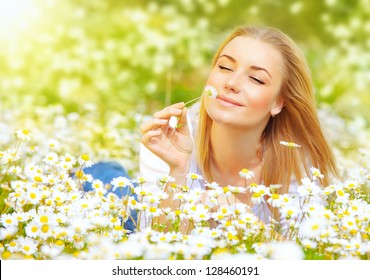 Photo of pretty blonde woman lying down in chamomile field, cute female enjoying smell of daisy, sweet teenager girl with closed eyes relaxed on flowers meadow, spring nature, having fun outdoor